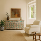 Lifestyle imagination of a hand-carved mango wood sideboard with green floral accents and vintage finish; perfect for bedroom furniture and bohemian interior style, 180 × 100 × 40 cm.