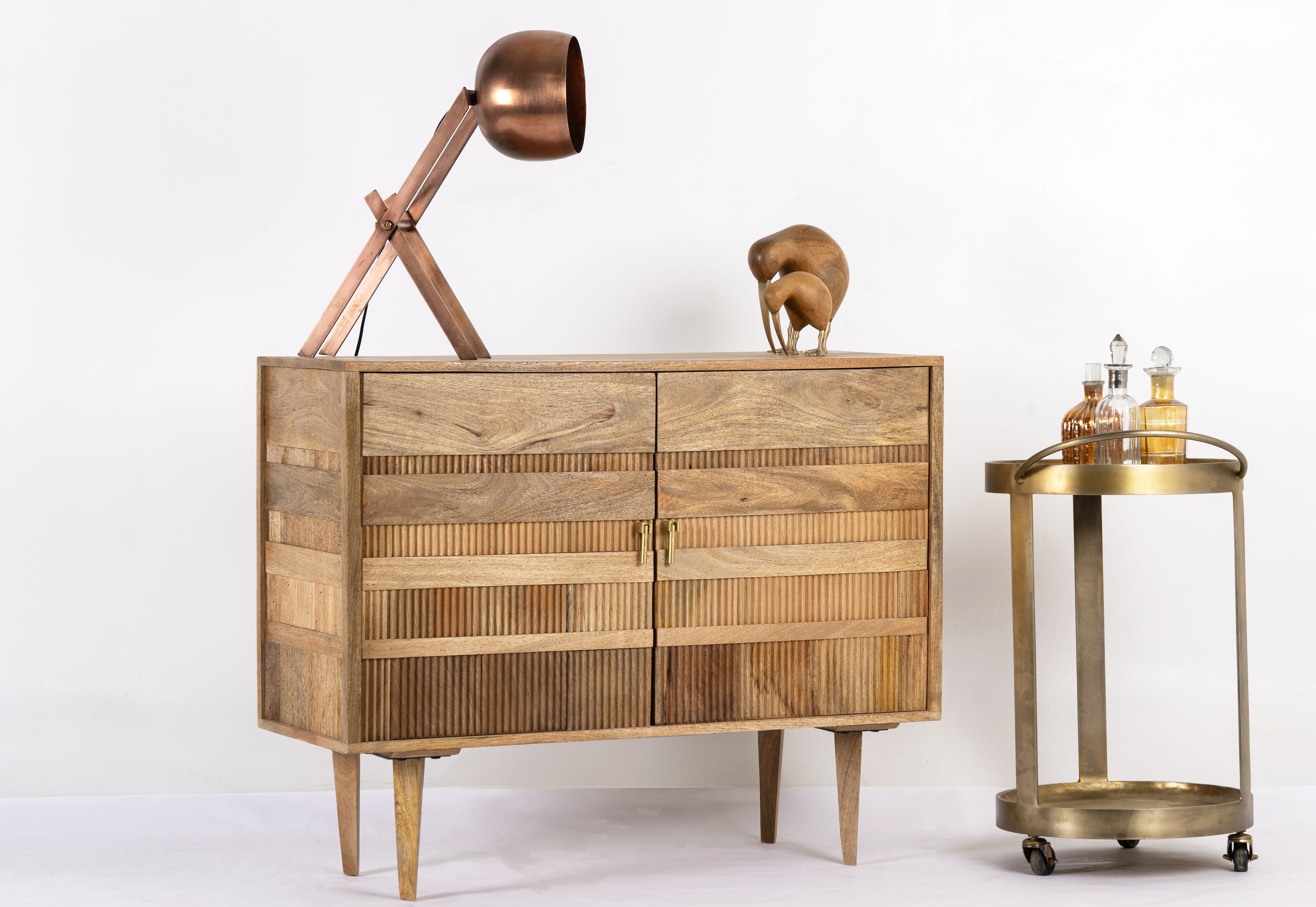 Side angle image of a hand-carved mango wood cabinet with 3D line-striped design and natural finish—vintage furniture blending artisanal detail and timeless style.