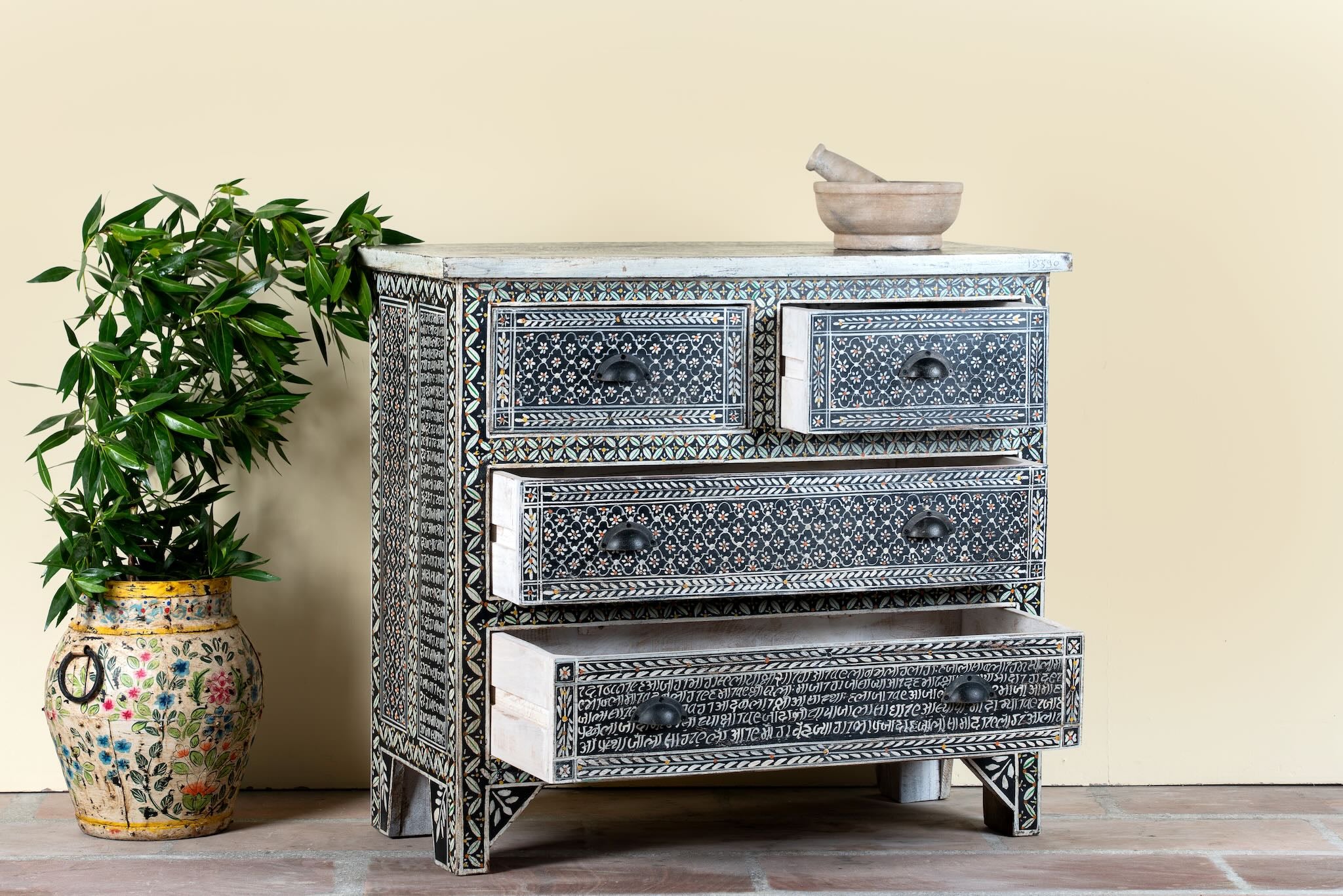 Side angle image with open drawers of a of a hand-painted Indian chest of drawers made from recycled wood – unique furniture featuring colourful motifs and antique craftsmanship.