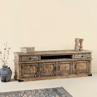 Side angle image of a hand-painted lowboard made of reclaimed wood with traditional Indian animal motifs, featuring drawers and cabinets for storage, rustic finish, and artisanal detailing.
