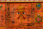 Close up image of a recycled teak wood chest with hand-painted Indian motifs in orange – sustainable furniture with vibrant character and cultural craftsmanship.