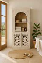 Lifestyle image of a hand-carved mango wood shelving unit with white washed finish and storage compartments – white washed wooden furniture ideal for vintage home accessories and Indian decor style.