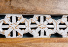 Close up image of a hand carved mango wood bench with floral backrest and spindle accents; rustic mango wood seating, 176 × 56 × 95 cm.