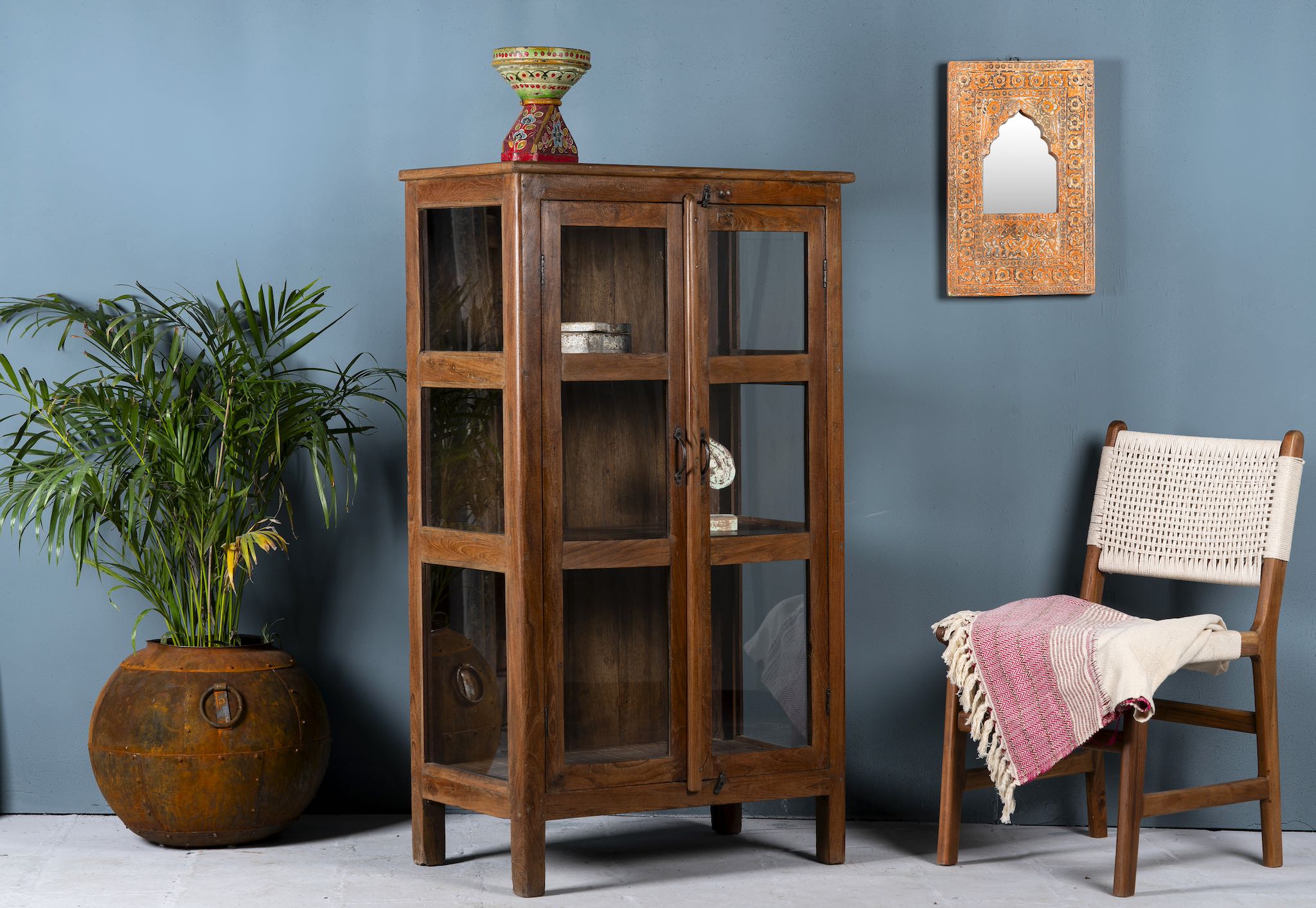 Side angle image of a compact reclaimed teak wood display cabinet with two glass doors and shelving – sustainable teak wood furniture combining functional design and unique character.