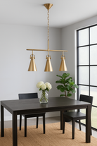 Lifestyle image of a three-light iron pendant lamp with brass finish and tapered design – minimalistic style lighting and iron pendant lights for modern interiors.