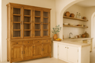 Lifestyle image with a two-part showcase cabinet made from reclaimed teak wood, featuring glass-panel upper doors for display, four drawers for storage, and lower cabinets with solid wood doors in a natural finish.