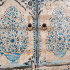 Close up image of a hand-painted wooden cabinet made from reclaimed wood with blue floral motifs – sustainable furniture with artistic charm and vintage appeal.