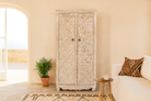 Life style image of a hand-carved mango wood wardrobe with whitewashed finish; wooden wardrobe perfect for living room furniture or bedroom storage, 180 × 90 × 40 cm.