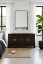 Lifestyle image of a handcrafted wood carved sideboard in black mango wood with four doors, versatile for bedroom furniture or living spaces, 180 × 40 × 90 cm.