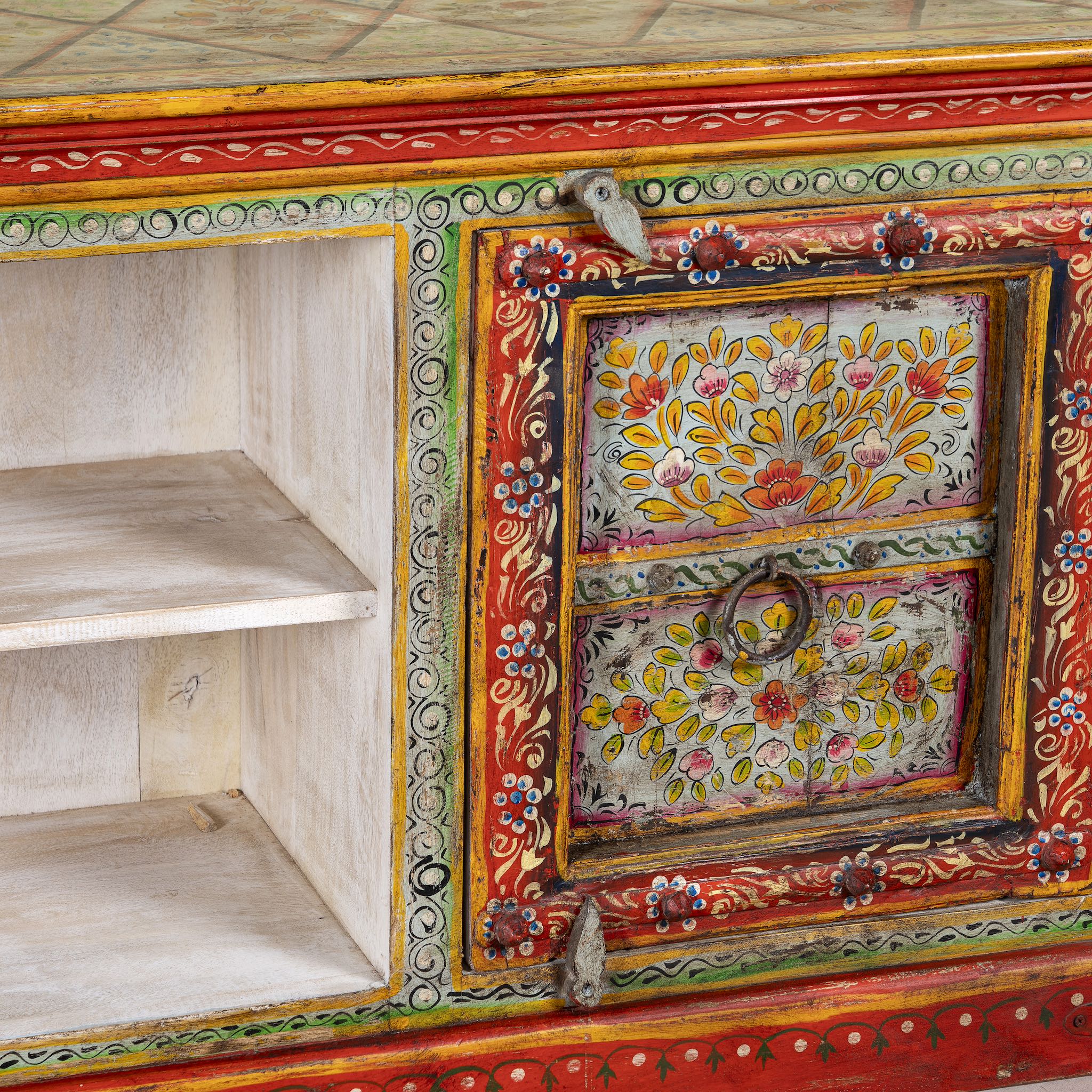 Close up image of a hand-painted reclaimed wood vintage lowboard with floral motifs – a colourful piece of sustainable furniture for artistic and rustic interiors.