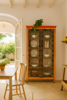 Lifestyle image of a hand-painted reclaimed wood showcase with floral motifs and glass doors – sustainable furniture combining vintage charm and traditional craftsmanship.
