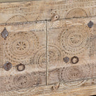 Close up image of a sideboard Taksh made from reclaimed teak wood, featuring carved antique Indian door fronts with circular mandala motifs. A unique piece of old door furniture combining Mediterranean style with traditional Indian craftsmanship.