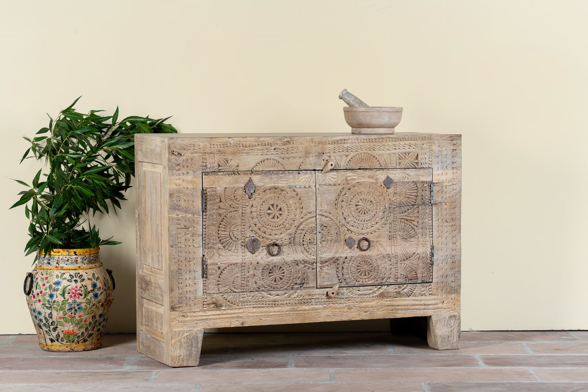 Side angle image of a sideboard Taksh made from reclaimed teak wood, featuring carved antique Indian door fronts with circular mandala motifs. A unique piece of old door furniture combining Mediterranean style with traditional Indian craftsmanship.