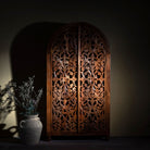 Lifestyle image of a hand carved wooden wardrobe with arc-shaped cabinet design in solid mango wood – Aranya model by Om Home & Garden