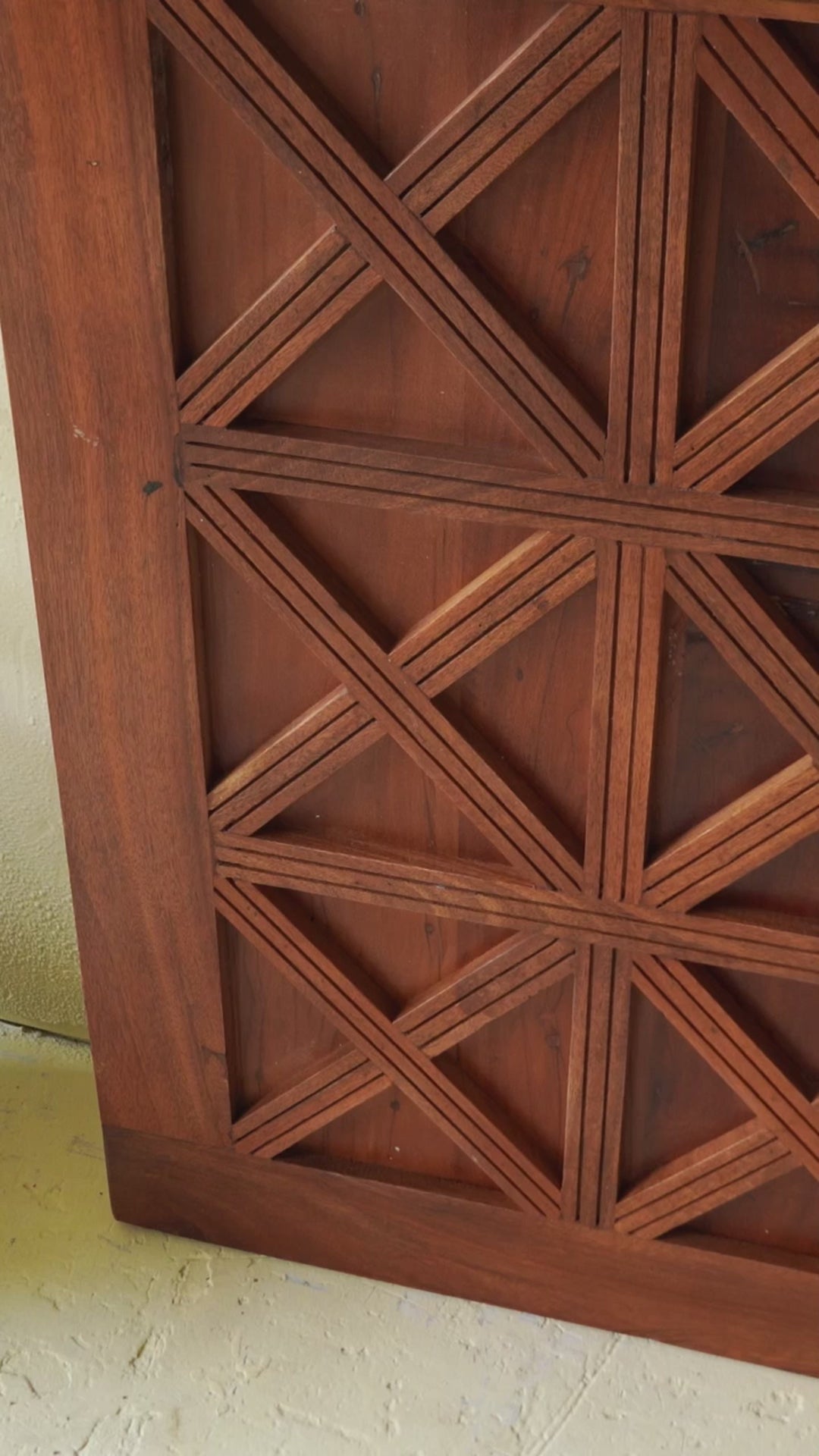 Sliding door panel crafted from reclaimed wood, featuring a bold geometric grid design with layered X-pattern carvings for a modern rustic look.