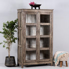 Side angle image of a handcrafted display cabinet made from reclaimed Teak wood with glass doors and Sanskrit motifs; sustainable and unique wooden furniture, 182 × 93 × 42 cm.