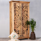 Side angle image of a hand-carved mango wood cupboard with Indian peacock design motifs, Mediterranean-style wardrobe; elegant mango wood furniture, 190 × 100 × 40 cm.