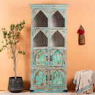 A hand-carved vintage mango wood shelf with a distressed pastel blue finish, featuring arch details and a mix of open shelves and closed compartments.
