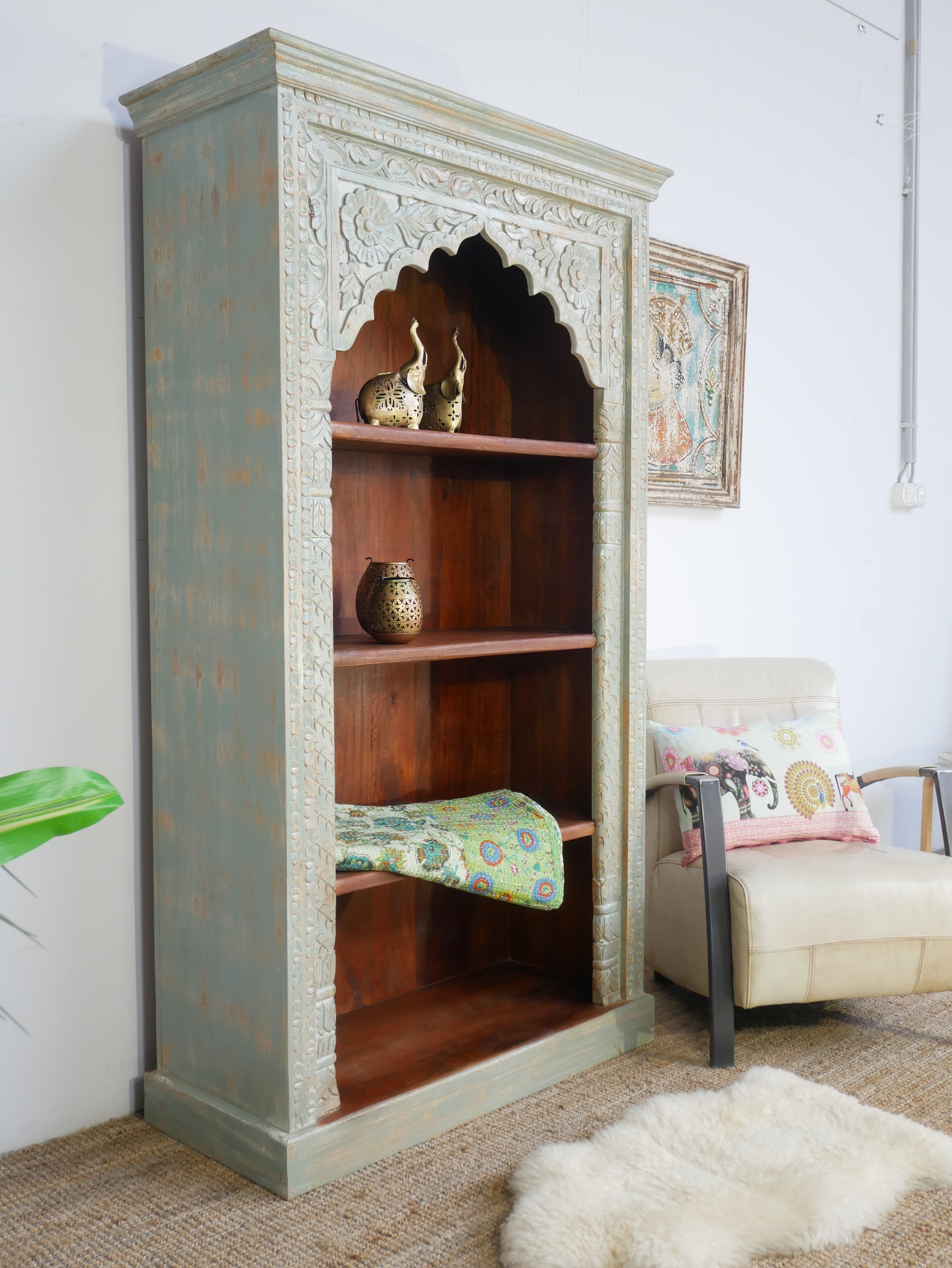 Side angle image of a hand-carved mango wood bookcase with Mediterranean design and open shelving – mango wood shelving and hand carved wooden furniture with natural finish.