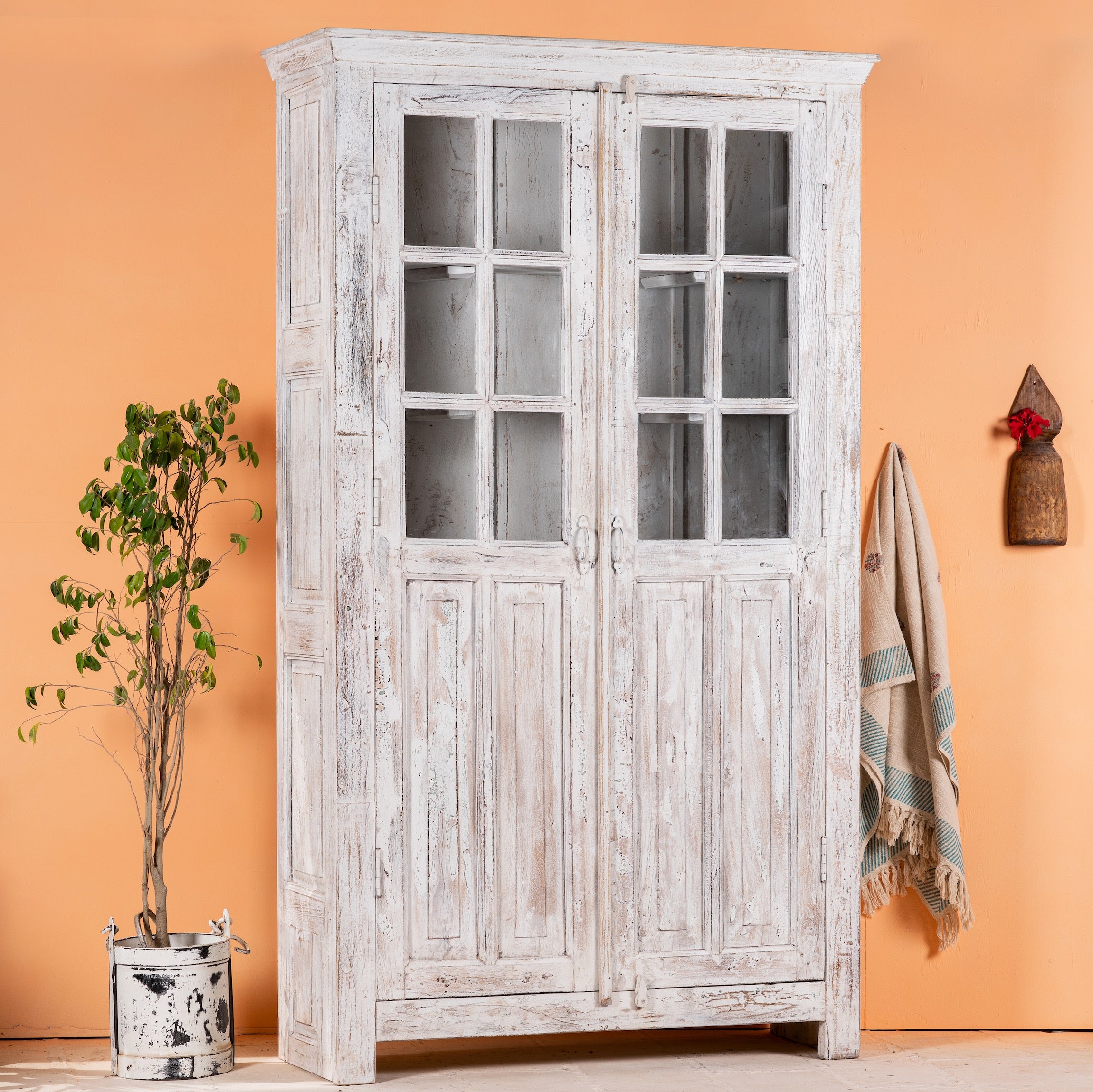 Side angle image of a refurbished antique teak wood display cabinet with whitewashed finish and glass doors – wooden display cabinet blending Mediterranean charm and timeless craftsmanship.