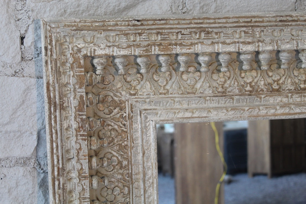 Close up image of a Vintage wall mirror with hand carved wooden mango wood frame; large rectangular mirror, 100 × 130 cm.