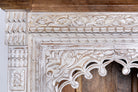 Close up image of a hand-carved mango wood bookshelf with arched frame and whitewashed finish – carved wooden furniture and mango wood shelving with Indian-inspired design.