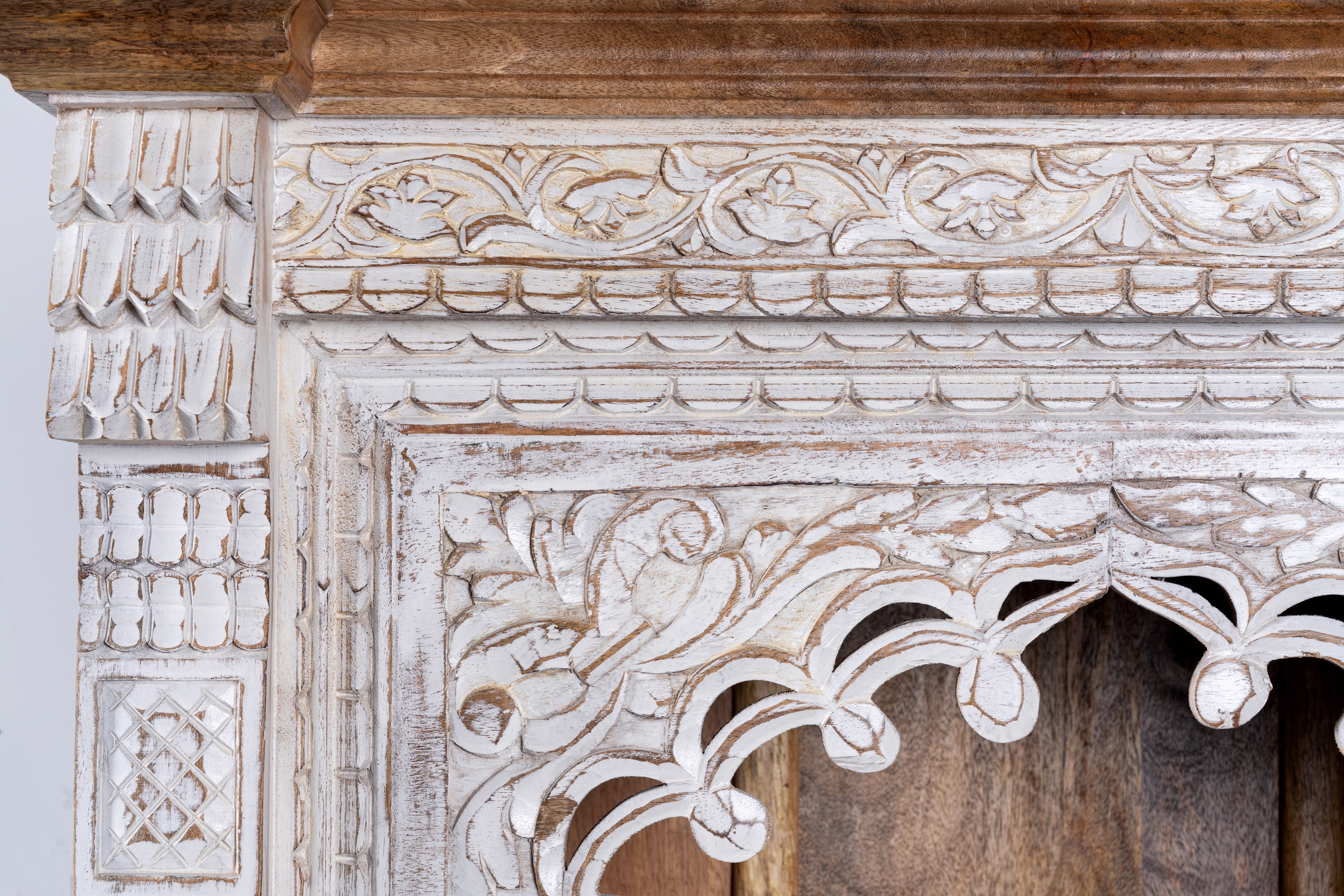 Close up image of a hand-carved mango wood bookshelf with arched frame and whitewashed finish – carved wooden furniture and mango wood shelving with Indian-inspired design.