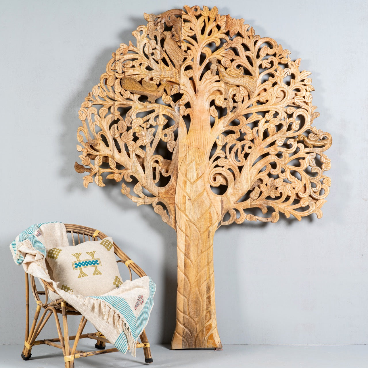 Life style image of a hand-carved mango wood wall panel with tree and bird motifs, vintage wall panels for boho chic living room, 180 × 150 × 10 cm.