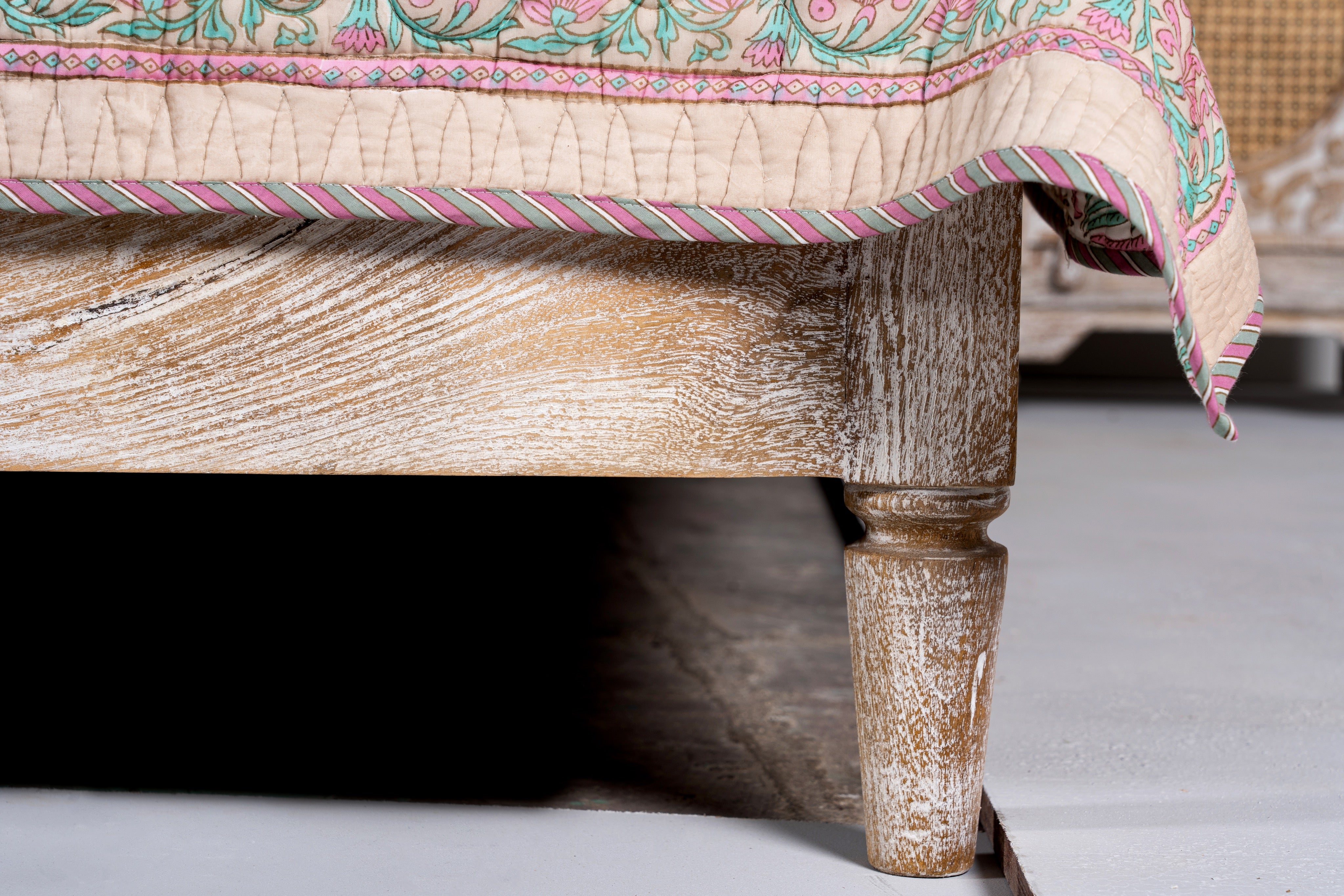 Close up image of a leg of a handcrafted Indian bed Tapti in solid mango wood with rattan panels, artisanal bedroom furniture, 180 × 200 cm.